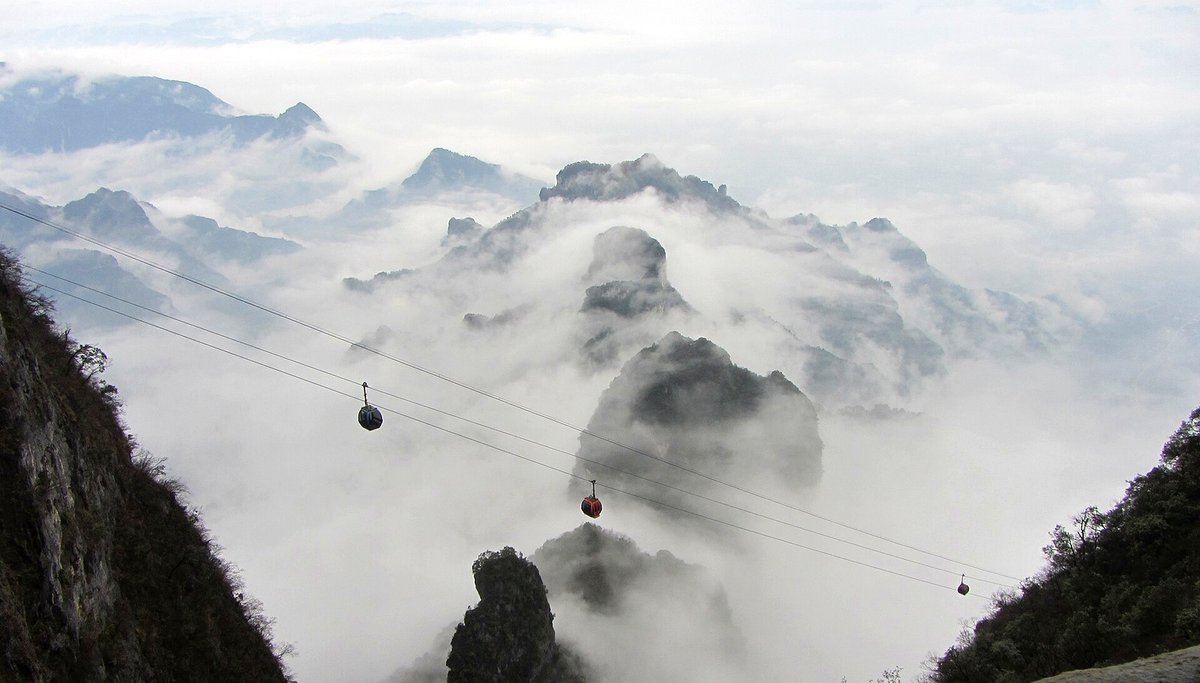 A sea of clouds between the peaks of Zhangjiajie with cable cars crossing
